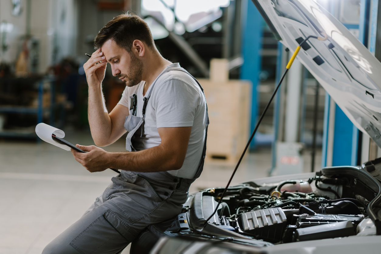 Worried mechanic having problems whit checklist in a workshop