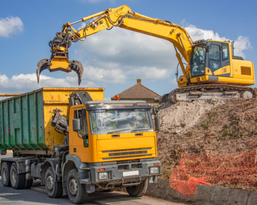 360 excavator fitted with grab unit loading a disposal lorry with debris from a site clearance