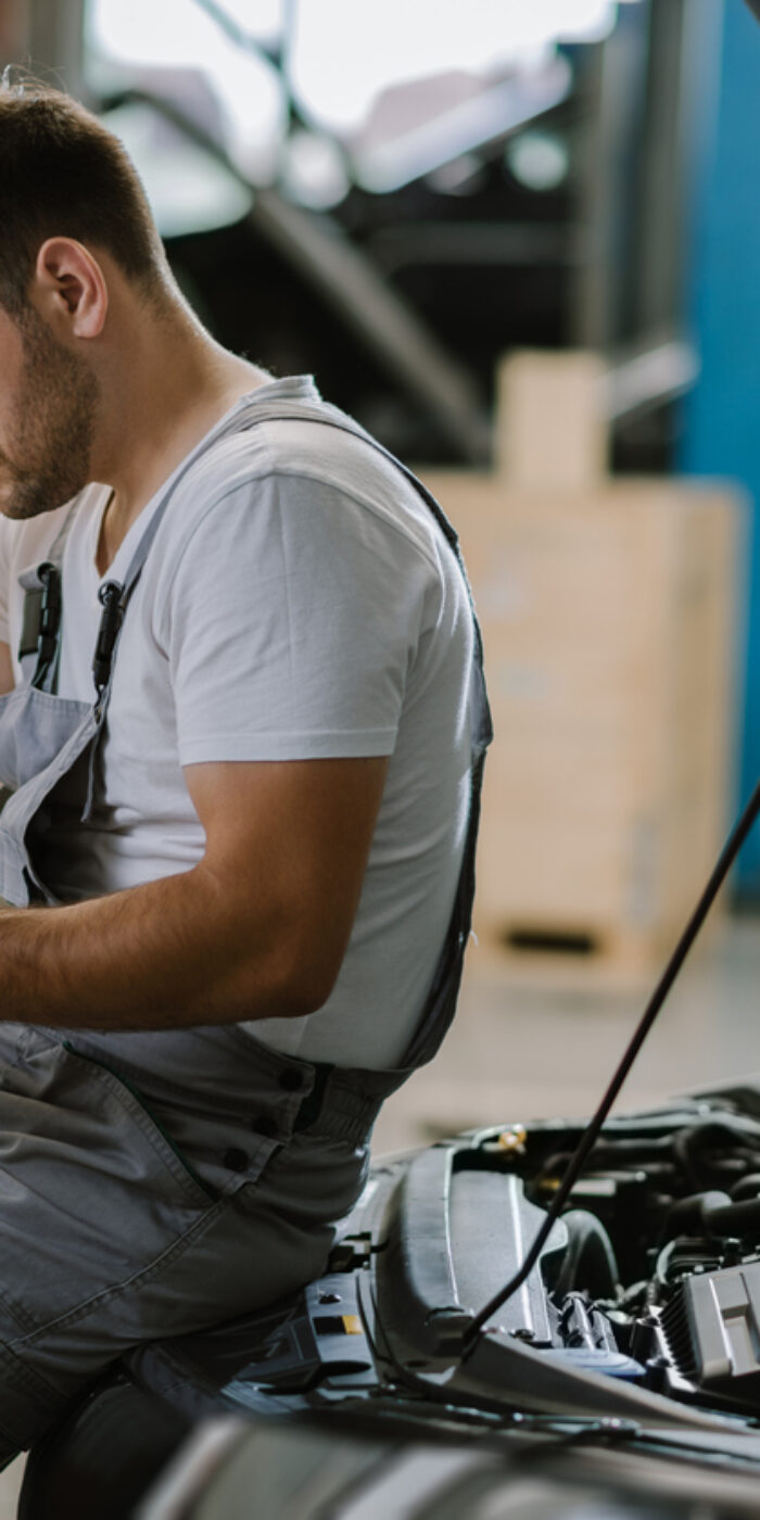 Young auto mechanic seeing potential problems while working on reports in a workshop