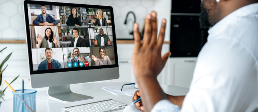 Video call, online conference. Over shoulder view of african american man at computer screen with multinational group of successful business people, virtual business meeting, work from home concept