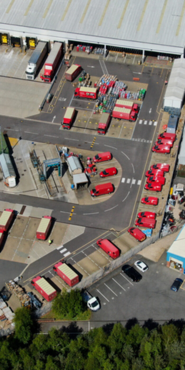 Drones eye view looking down on a Royal mail postal sorting depot in England showing lorries and vans being loaded