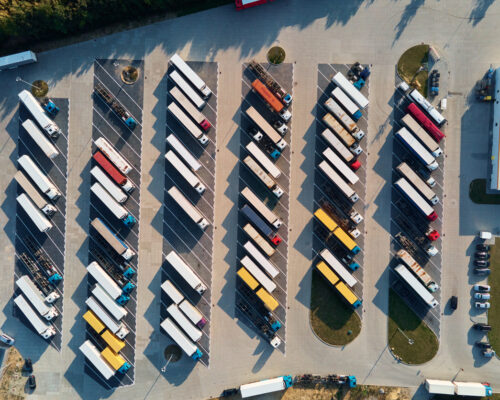 Parking lot for semi trucks, top view. Aerial view of Truck trailers parked for waiting loading on factory. Logistics and shipping