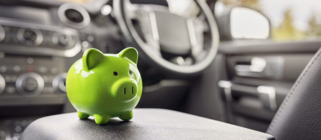 Green piggy bank money box in car interior, vehicle purchase, insurance or driving and motoring cost
