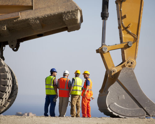 Workers talking by machinery in quarry