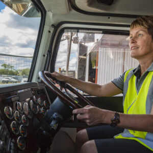 Empowered happy woman driving a truck in the transport industry wearing high visibility clothing